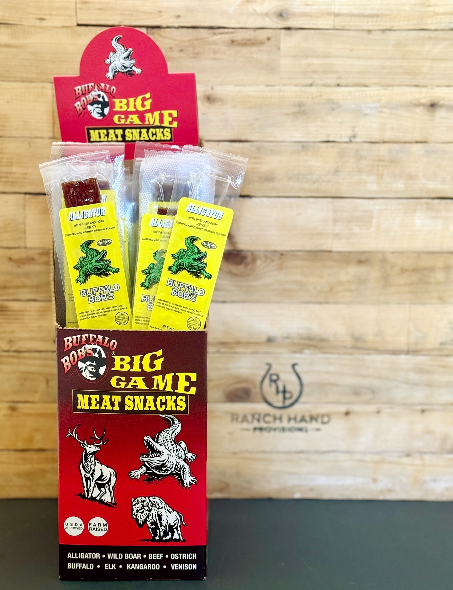 Box of 24 Alligator Jery Sticks with a wooden cutting board background