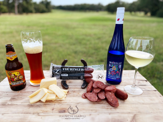Pairings of meats, cheeses, beer, and wine sit on a cutitng board.