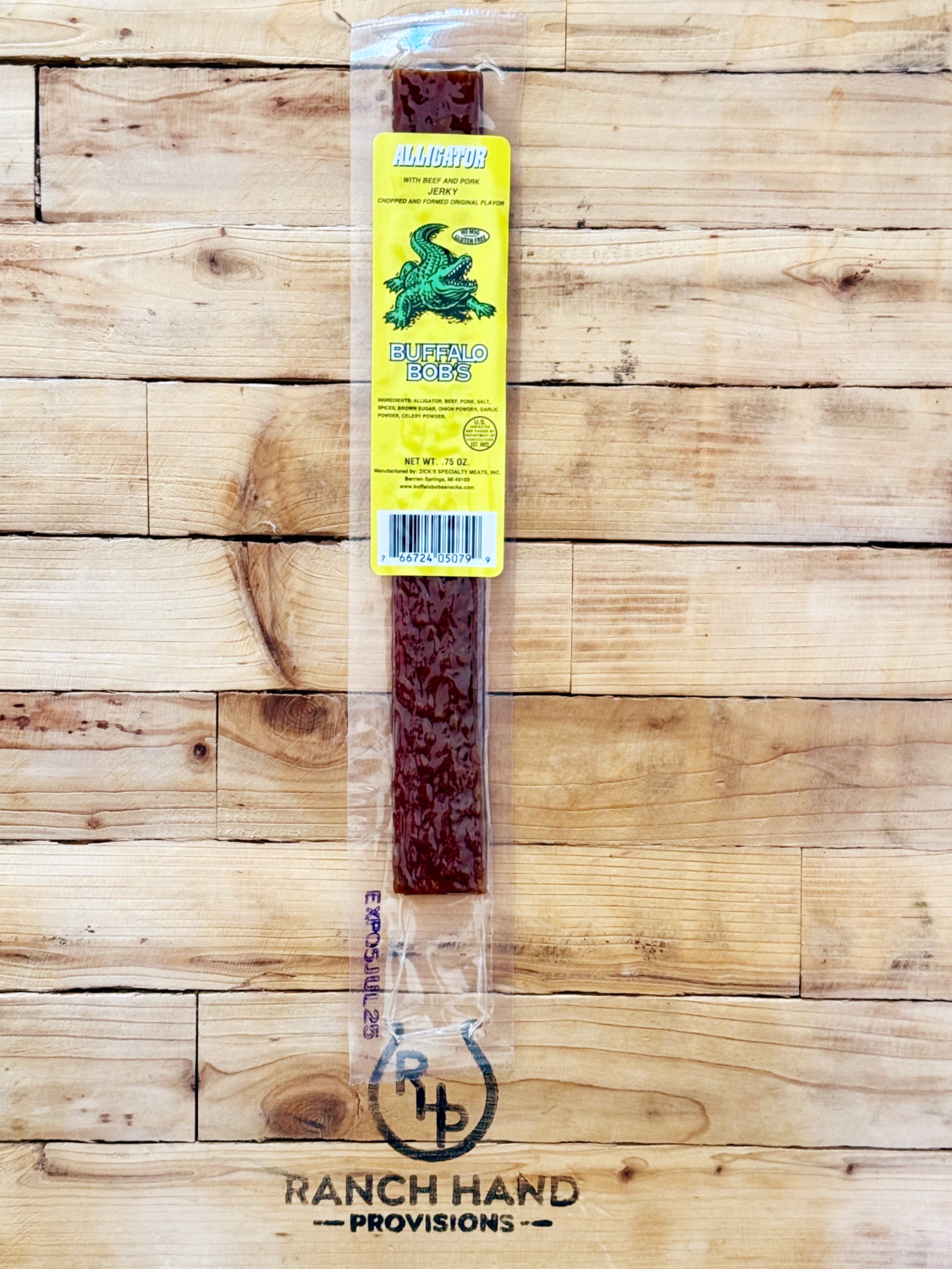 Packaged alligator jerky on a wooden background, with the brand logo 'Ranch Hand Provisions' visible on the packaging.